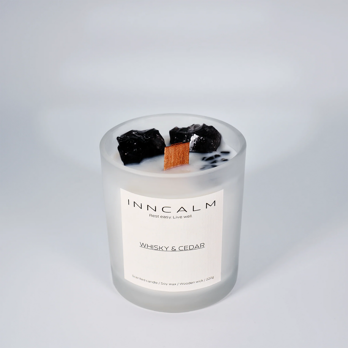 INNCALM Whiskey & Cedar jar candle, showcasing its minimalist, modern design and warm, inviting amber glow when lit.