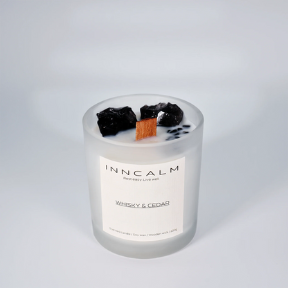 INNCALM Whiskey & Cedar jar candle, showcasing its minimalist, modern design and warm, inviting amber glow when lit.